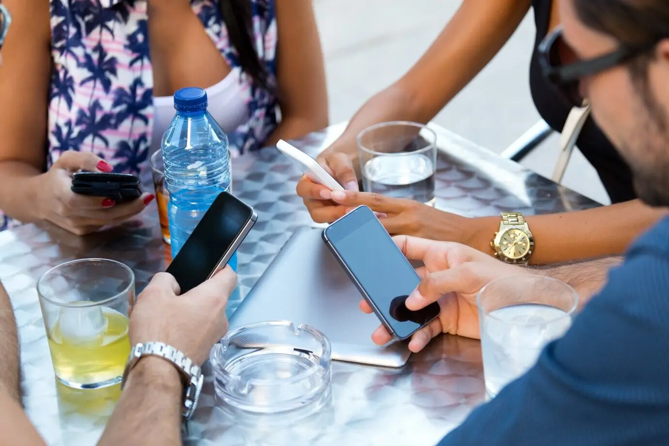 Young women sending SMS messages on their phones while drinking.