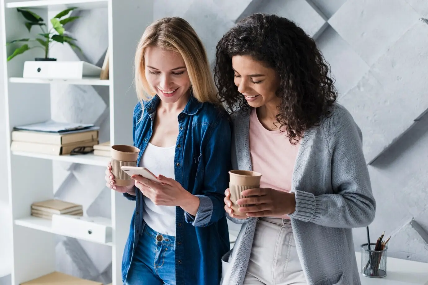 Ethnic female office workers on a coffee break with a smartphone.